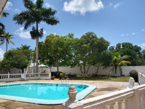 a swimming pool in a yard with a fence and trees at Habitaciones Familiares Hacienda Botero in Turbaco