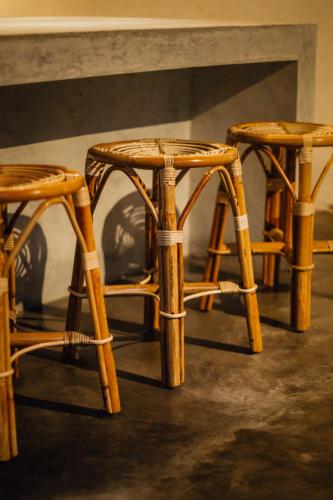 a group of three bamboo chairs sitting next to a wall at Adara Homestay in Banyuwangi