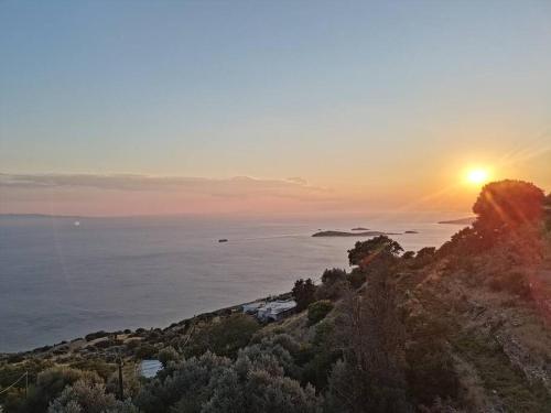 a sunset over the ocean with the sun setting on a hill at Melissa Houses in Apróvaton