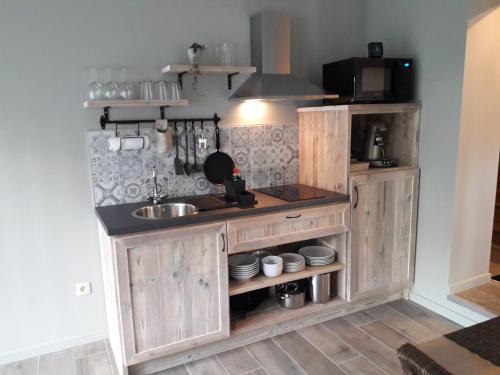 una cocina con armarios de madera y fregadero en Het Innerhof, en Opglabbeek
