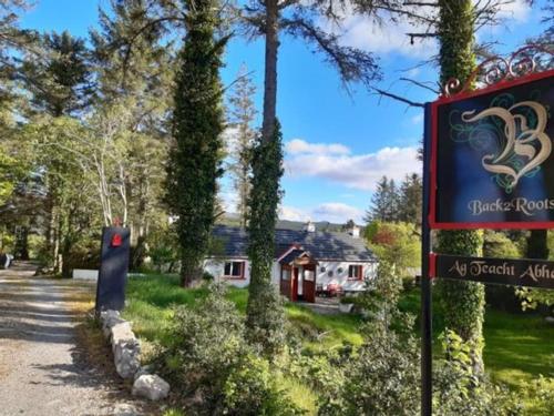 ein Schild vor einem Haus mit Bäumen in der Unterkunft Back2Roots - Beautifully Restored Cottage, Doochary in Doochary