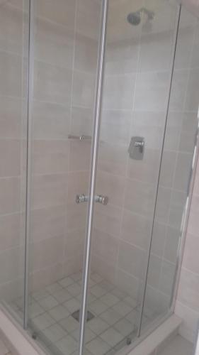 a shower with a glass door in a bathroom at Greenpark Apartment in Kempton Park