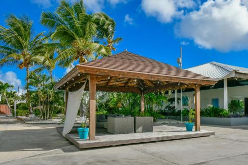 a pavilion in front of a house with palm trees at Aruba Blue Village Hotel and Apartments in Palm-Eagle Beach