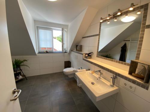 uma casa de banho com um lavatório, um espelho e um WC. em Waldhotel Am Jäger em Wesel