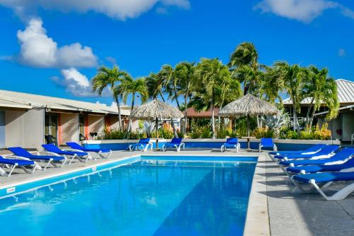 a pool with chairs and umbrellas at a resort at Aruba Blue Village Hotel and Apartments in Palm-Eagle Beach