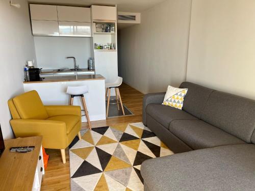 un soggiorno con divano e sedia e una cucina di Appartement calme et propre avec vue sur la mer a Saint-Laurent-du-Var