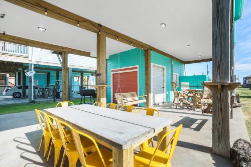 Sea Glass Cottage في Crystal Beach: طاولة خشبية وكراسي صفراء على الفناء