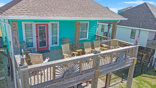 Sea Glass Cottage في Crystal Beach: منزل أزرق مع كراسي هزاز على سطح السفينة