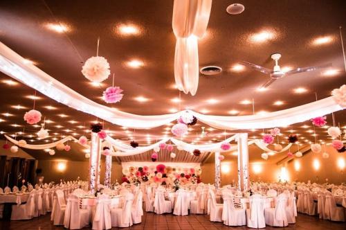 バヤにあるMalom Club Panzióの白いテーブルとピンクの花が飾られた宴会場