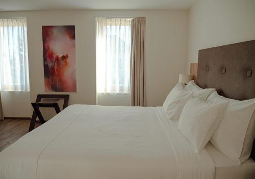 a bedroom with a large white bed with white pillows at Auberge Le Relais in Chavannes-de-Bogis