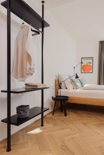a bedroom with a bed and a black shelf with a shirt at Marktbar Studios - Boutique Aparthotel in Innsbruck