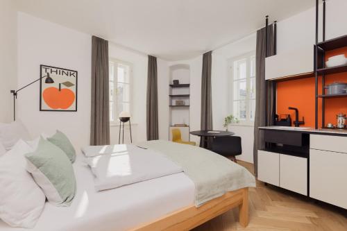a bedroom with a large white bed and a kitchen at Marktbar Studios - Boutique Aparthotel in Innsbruck