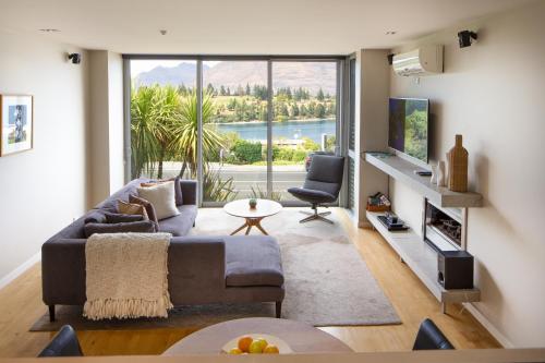 a living room with a couch and a large window at Hello QT Pounamu in Queenstown