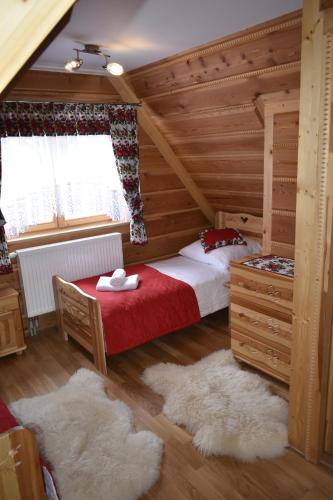 ein Schlafzimmer mit einem Bett mit einer roten Decke in der Unterkunft Domek Góralski POD LASEM in Witów