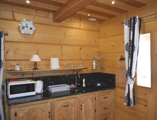 a kitchen with wooden walls and a counter with a microwave at Domek Góralski POD LASEM in Witów