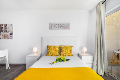 um quarto com uma cama com lençóis amarelos e flores em Praia da Rocha, 4G Jardins da Rocha, Sunny Studio, Air Conditioning, two Pools, Internet, Parking, by IG em Portimão