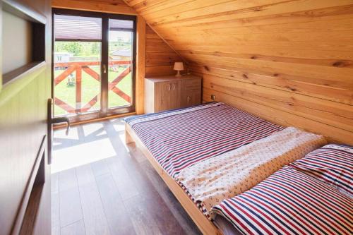 a large bed in a wooden room with a window at Semi-detached house, Niechorze in Niechorze