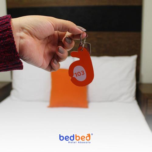 une main portant une étiquette rouge sur un lit dans l'établissement Bed Bed Hotel Estrella, à Torreón
