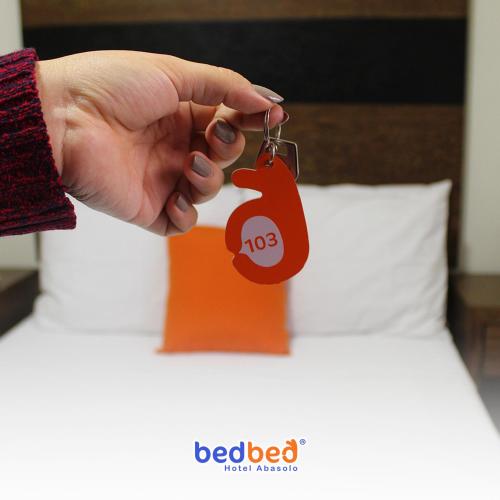 a persons hand holding a red tag on a bed at Bed Bed Hotel Estrella in Torreón