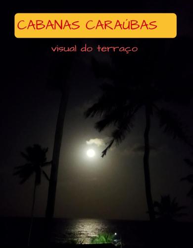 a view of the ocean at night with palm trees at Cabanas Caraúbas - frente para o mar, ar & Tv in Maxaranguape