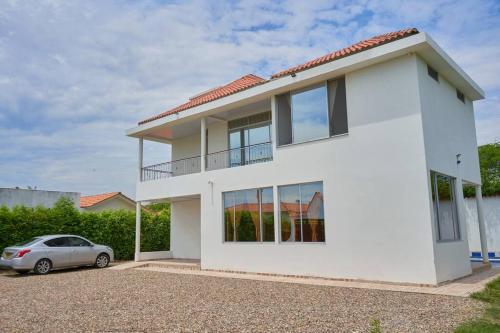 a white house with a car parked in front of it at Casa vacacional Girardot 5 habit in Girardot