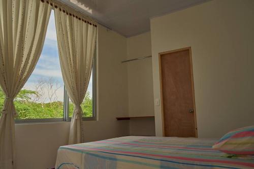 um quarto com uma cama e uma grande janela em Casa vacacional Girardot 5 habit em Girardot