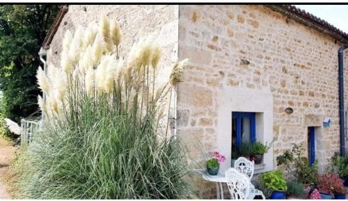 un bâtiment en pierre avec une table, des chaises et des plantes dans l'établissement Gite de Rosaraie, à Beaulieu-sur-Sonnette