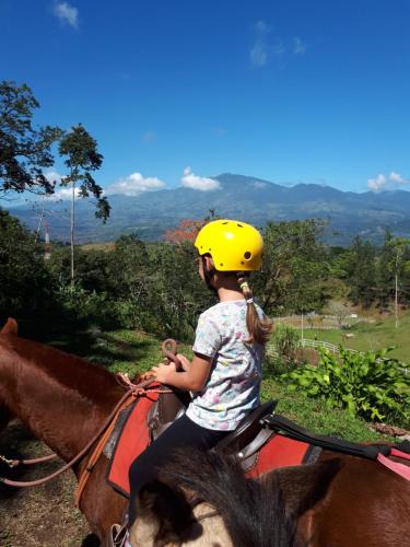 a little girl riding on the back of a horse at Finca Tres Equis - Farm and Forest in Tres Equis