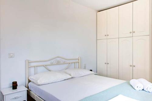 a white bedroom with a bed and white cabinets at Casa di Roza in Corfu