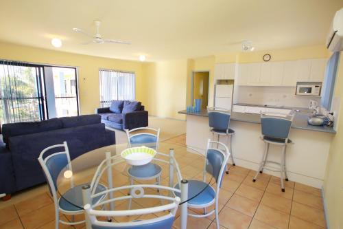 a living room with a couch and a table and chairs at Nautilus Apartments Merimbula in Merimbula