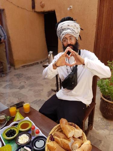 a woman sitting at a table taking a picture at Maison d'hôte sirwaji in Assa