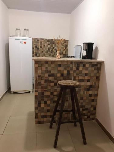a counter in a kitchen with a stool and a refrigerator at Residencial Vovó Lelé in Imbassai