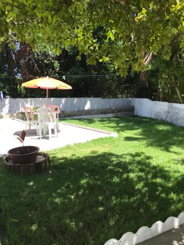a patio with an umbrella and a table and chairs at Residencial Vovó Lelé in Imbassai