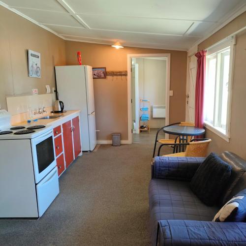 eine Küche und ein Wohnzimmer mit einem Sofa und einem Tisch in der Unterkunft Oturehua Railway Hotel Cottage in Oturehua