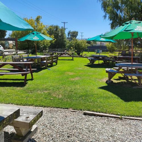 a group of picnic tables with umbrellas in a park at Oturehua Railway Hotel Cottage in Oturehua