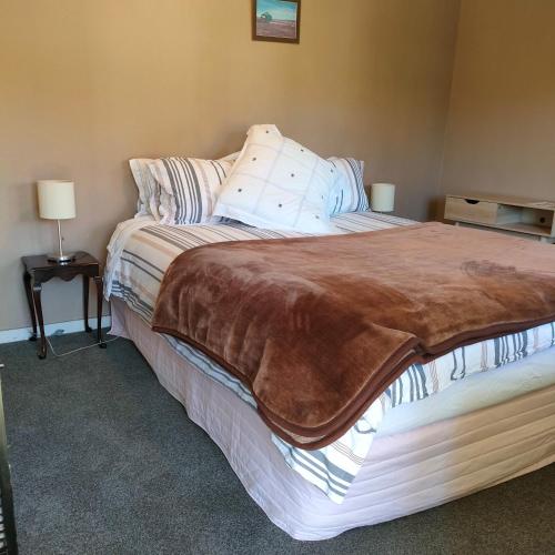 a bedroom with a bed with a brown blanket on it at Oturehua Railway Hotel Cottage in Oturehua