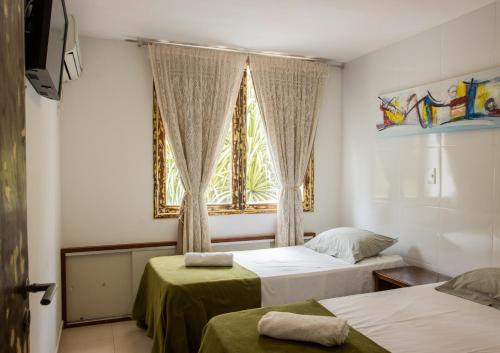 a bedroom with two beds and a window at Bangalô Pipa Resort in Pipa