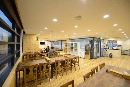 a restaurant with wooden tables and chairs and a person at Dunsan Graytone Hotel in Daejeon