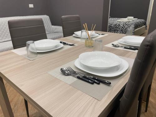 a wooden table with white plates and utensils on it at B&B Miramare Suite Borgo in Taranto