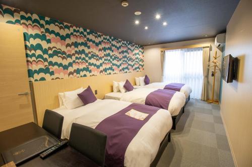 ein Hotelzimmer mit drei Betten in einem Zimmer in der Unterkunft Stay SAKURA Kyoto Zen in Kyoto