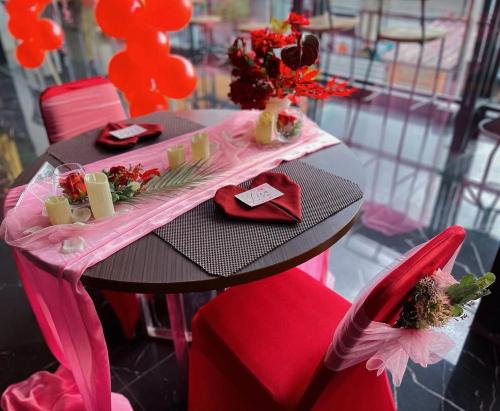 une table avec des chaises rouges et une table rose avec des fleurs dans l'établissement Golden Palace Hotel, à Batu Merah