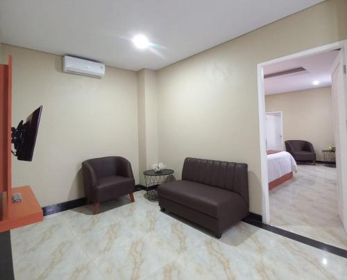 a room with a couch and a bed and a mirror at Grand Avira Hotel in Batu Merah