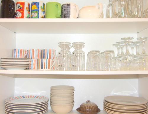 a shelf with plates and glass vases on it at Sunlit Loft Apartment Riga in Rīga