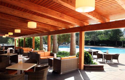 a patio with tables and chairs and a pool at Golden Port Salou & Spa in Salou