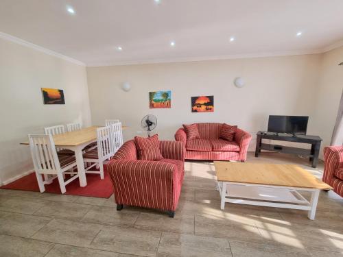 a living room with couches and a table and a television at Mwaiseni Maisonettes apartments in Ndola