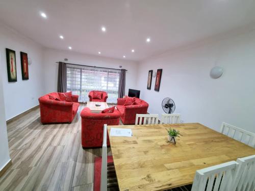 a living room with red chairs and a wooden table at Mwaiseni Maisonettes apartments in Ndola