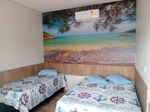 two beds in a room with a painting on the wall at Casa Família Porto in Olímpia