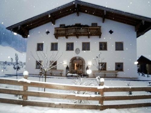 a large white building with a fence in the snow at Freundsheimhof in Kramsach