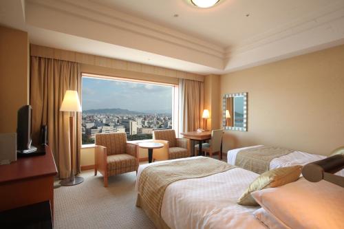 a hotel room with two beds and a large window at JR Hotel Clement Takamatsu in Takamatsu