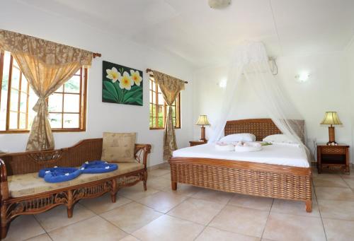 ein Schlafzimmer mit einem Bett, einem Sofa und Fenstern in der Unterkunft Le Surmer Self Catering Chalets in La Digue